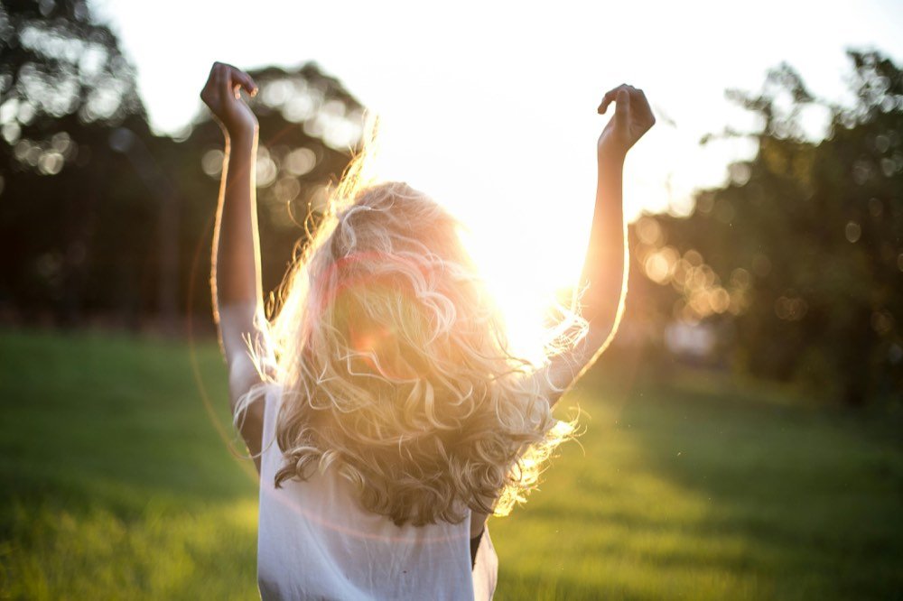A woman with her arms flung up into the sun
