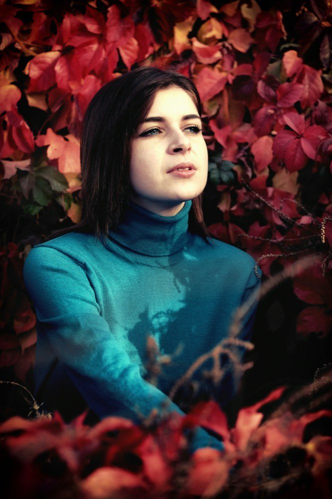 A woman among red leaves, looking straight at you