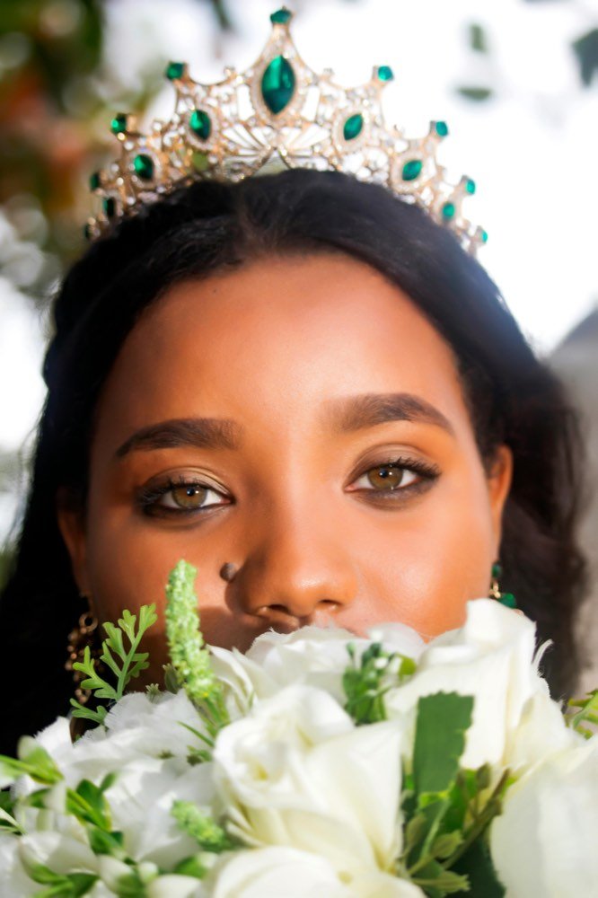 A woman in a crown, holding white flowers