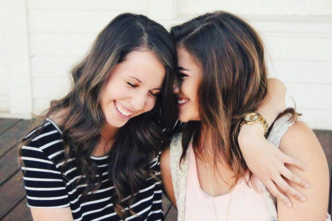 Two women laughing, foreheads touching