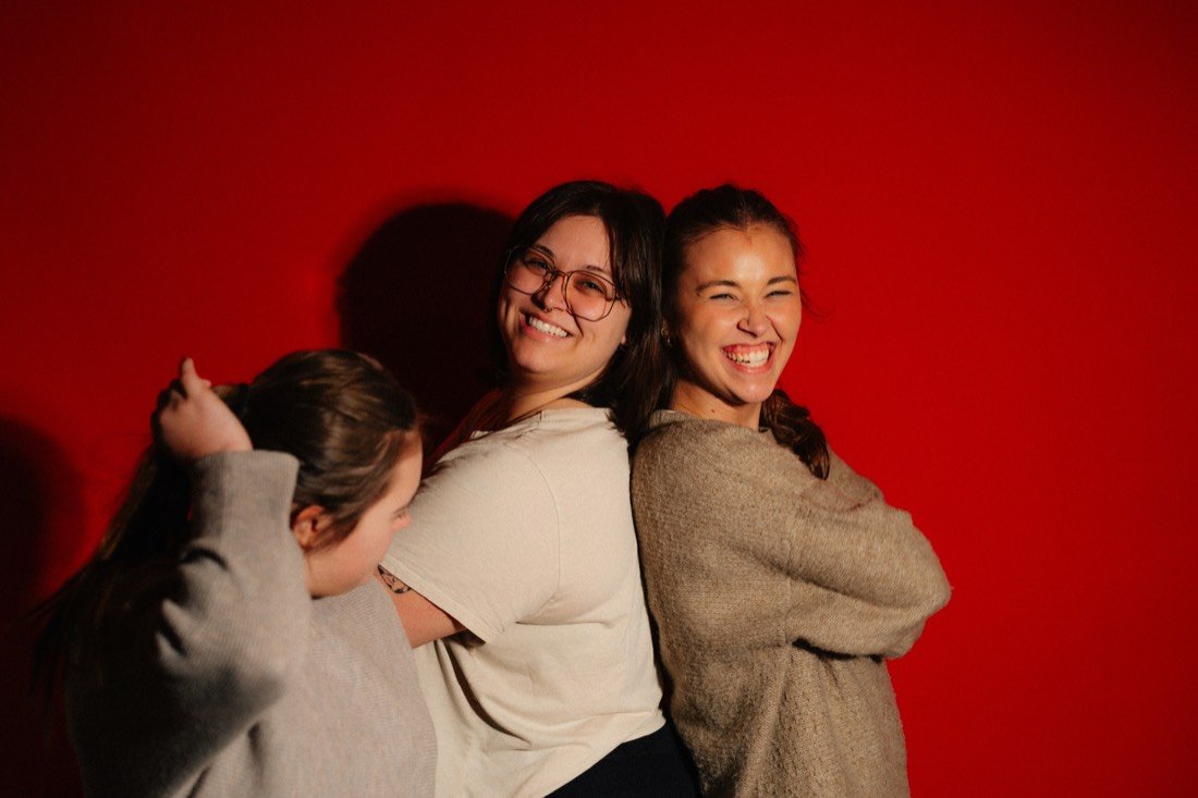 Three women laughing, arms around each other