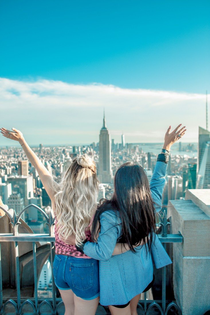 Two women with their arms raised high above a city